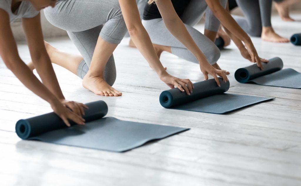 Drei Frauen rollen ihre Yogamatten aus und bereiten sich auf die Yoga-Praxis bei Yoga Blue in Stuttgart vor.
